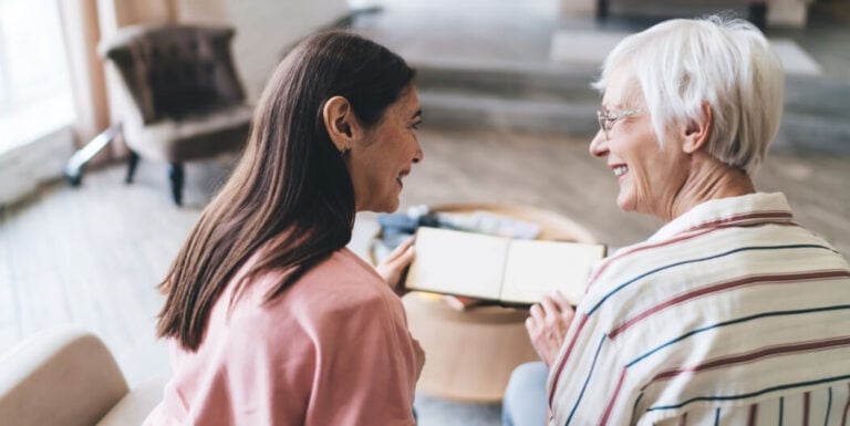 Nursing Staff Reviewing Photo Album With Resident at Memory Care Facility